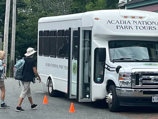 Menschen, die auf einen weißen Shuttlebus der Acadia National Park Tours zugehen.