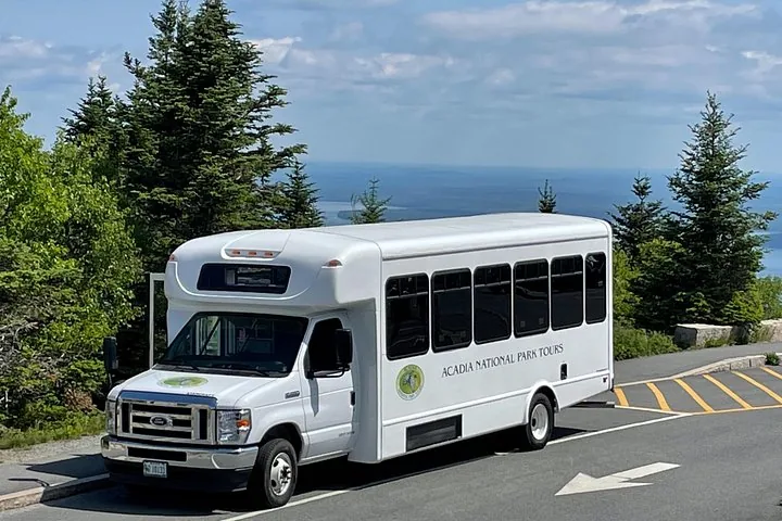 Acadia National Park Tours bus parked on a hill overlooking the ocean.